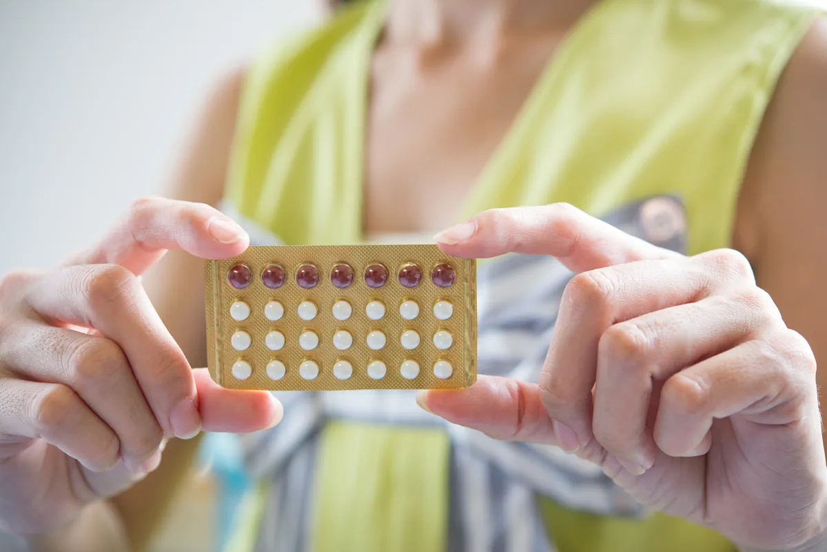 Une femme qui montre des pilules contraceptives